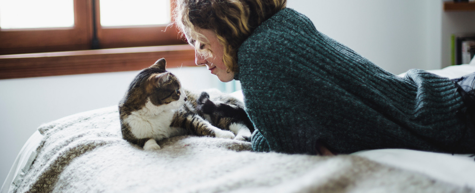 Frau und Katze auf dem Bett